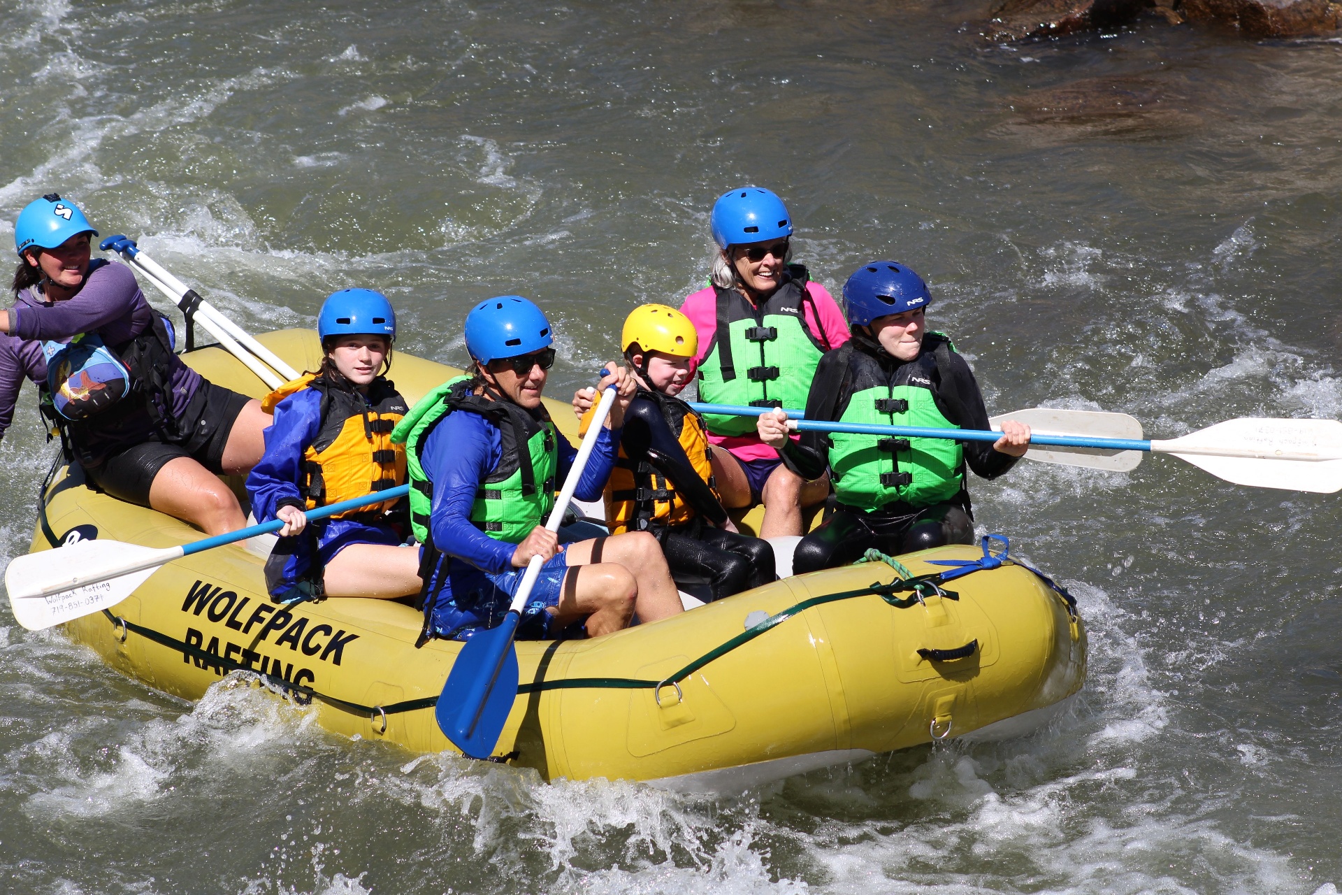 Family paddling a yellow Wolfpack raft through Bighorn Sheep Canyon