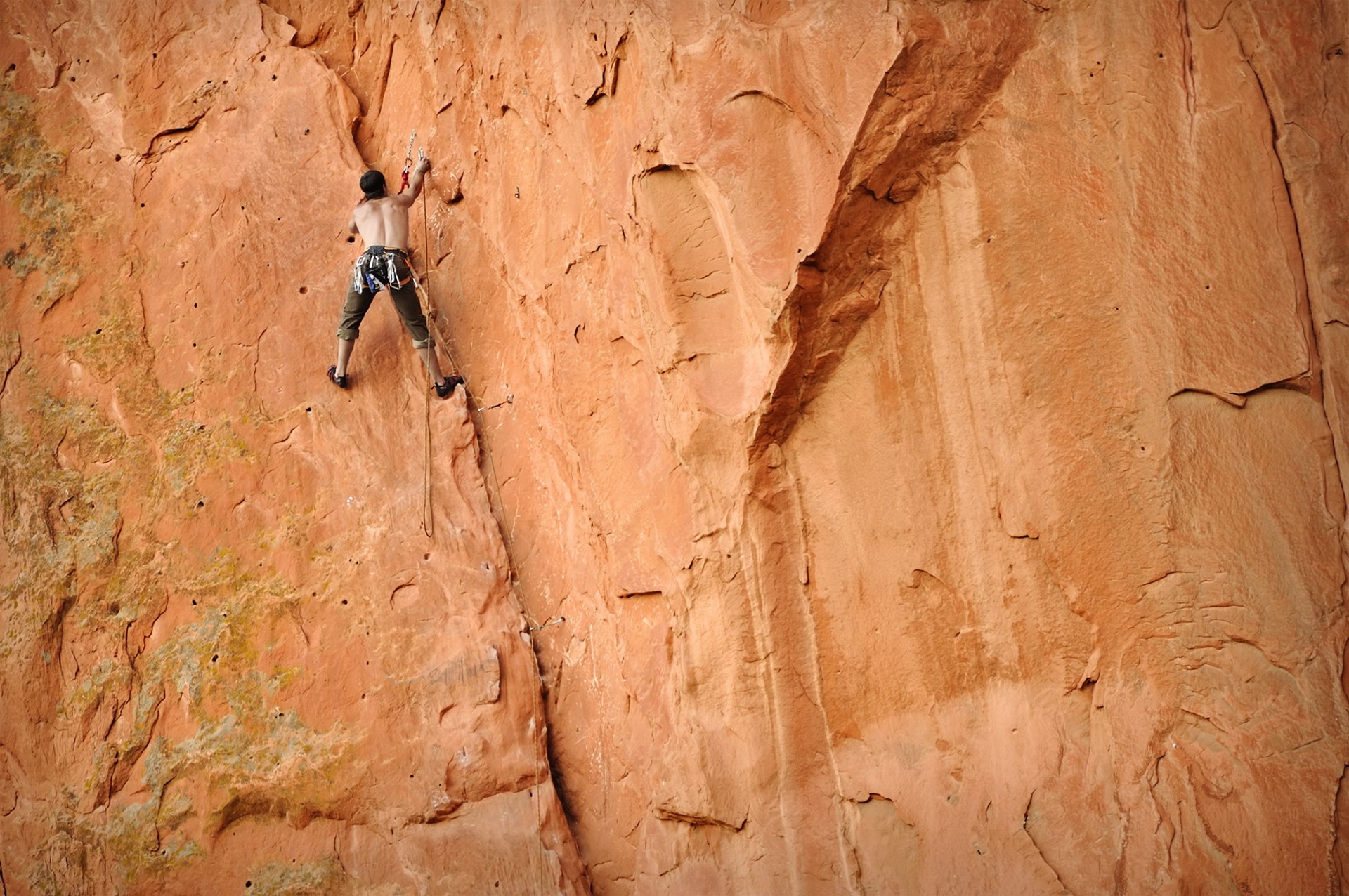 Guided Rock Climbing Rock climber ascending a tall red sandstone wall on a rope in Colorado's Red Rock Country